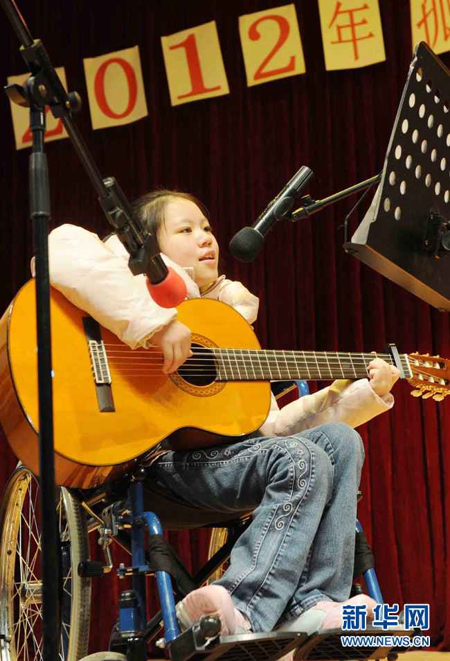 16岁的残疾女孩何健莹坐在轮椅上一边弹吉他一边唱歌.